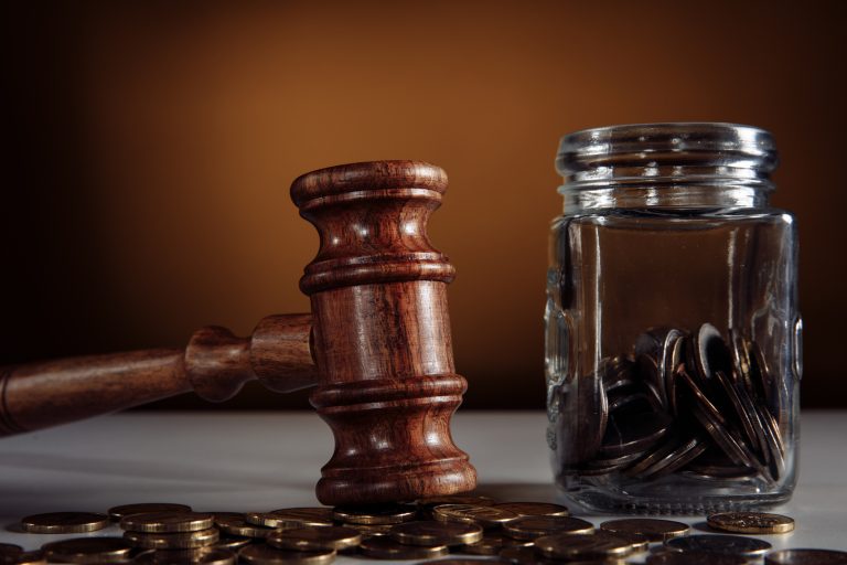 Coins from a jar and legal gavel on a table