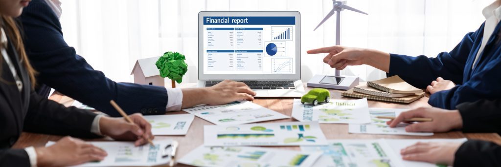 Contador revisando reportes de contabilidad verde con métricas ambientales y financieras en oficina corporativa