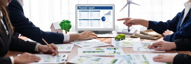 Contador revisando reportes de contabilidad verde con métricas ambientales y financieras en oficina corporativa