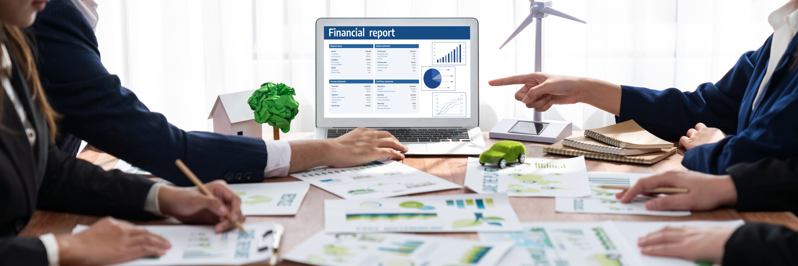 Contador revisando reportes de contabilidad verde con métricas ambientales y financieras en oficina corporativa