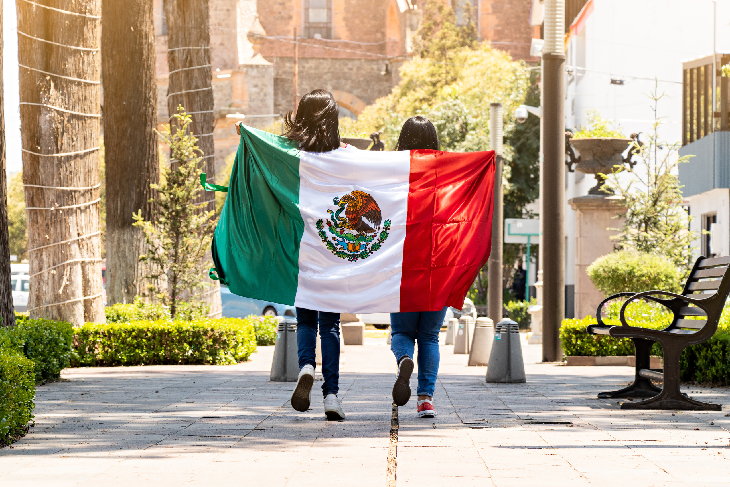 Dos mujeres mexicanas con la bandera de México en la espalda
