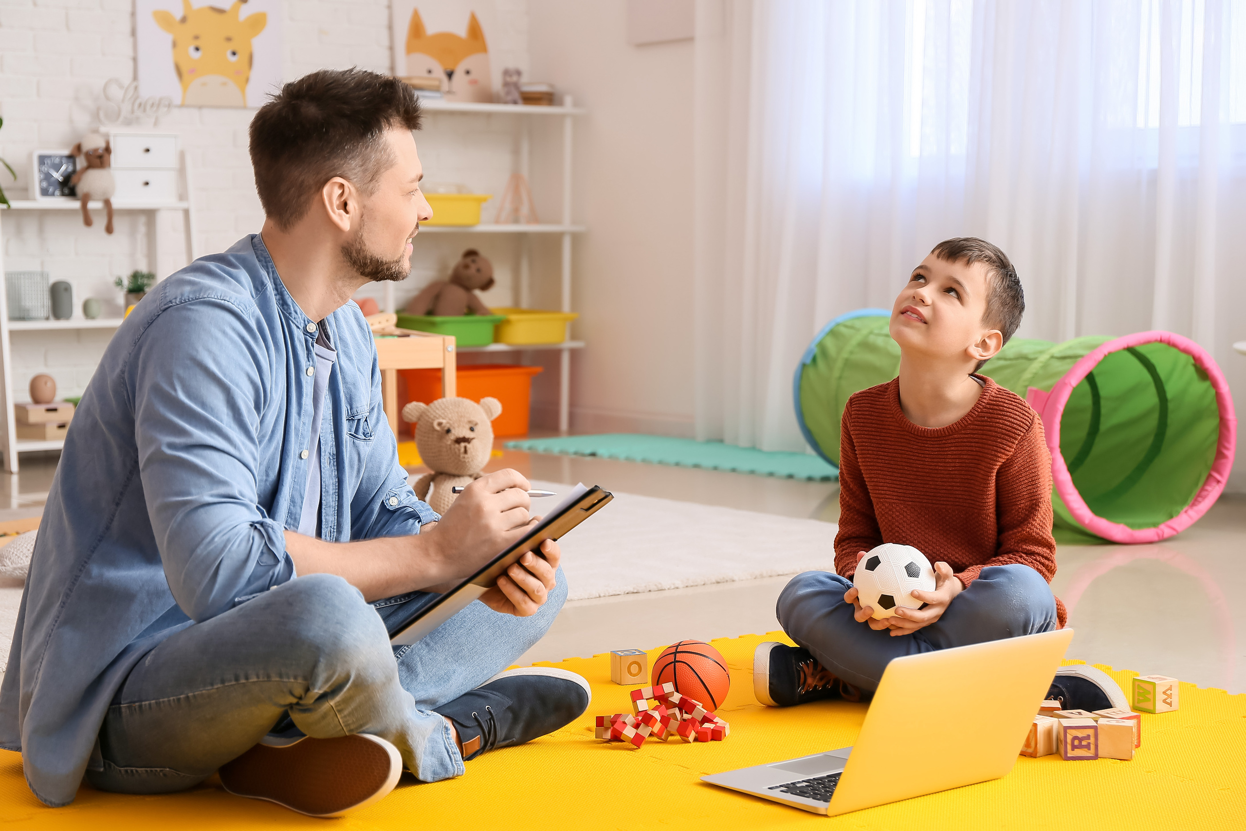 Niño en una sesión de psicoanálisis con su terapeuta que lo observa a su altura