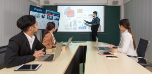 Equipo de trabajo discutiendo escenarios financieros frente a un tablero con proyecciones